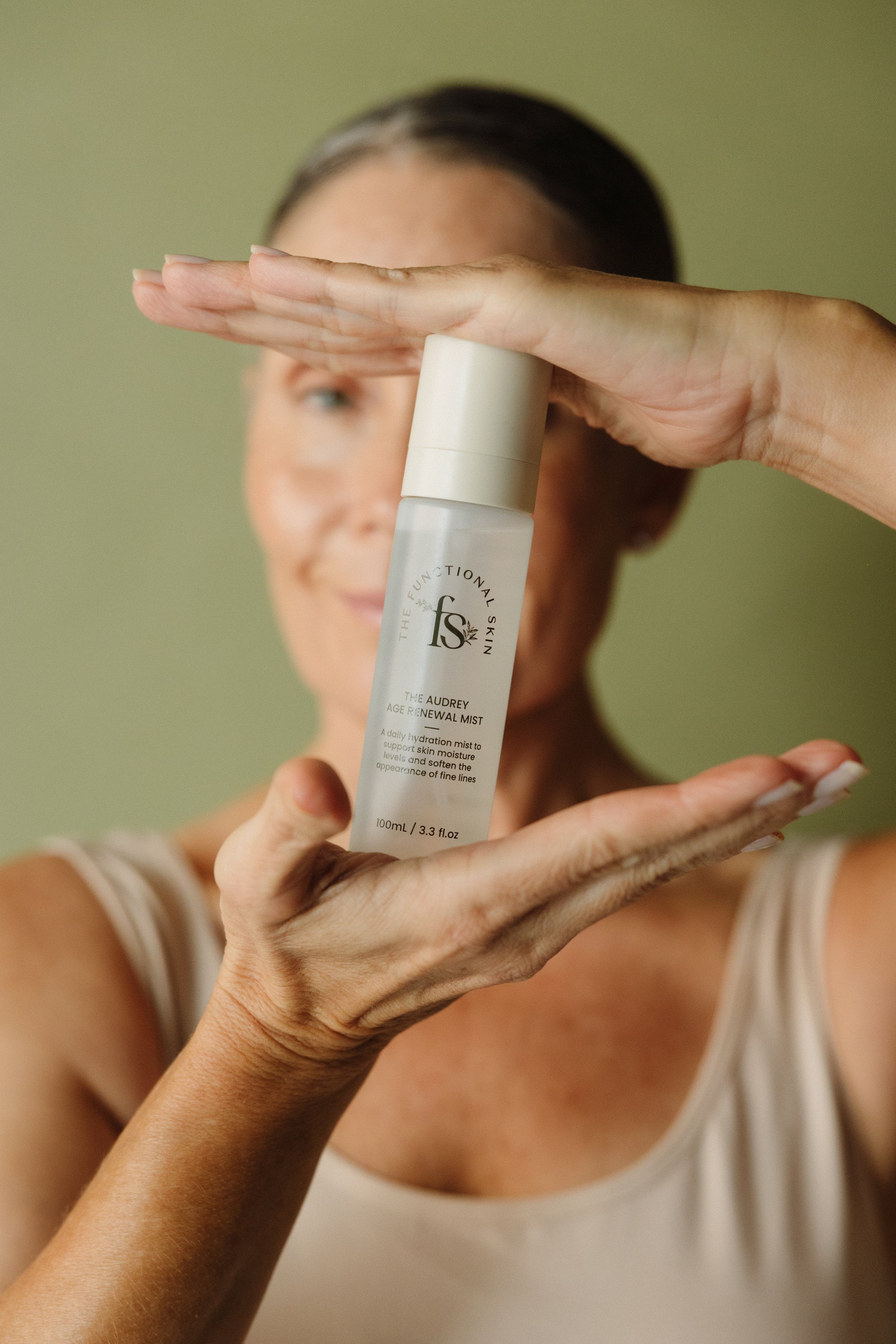 Person holding The Audrey Age Renewal Mist with a blurred background