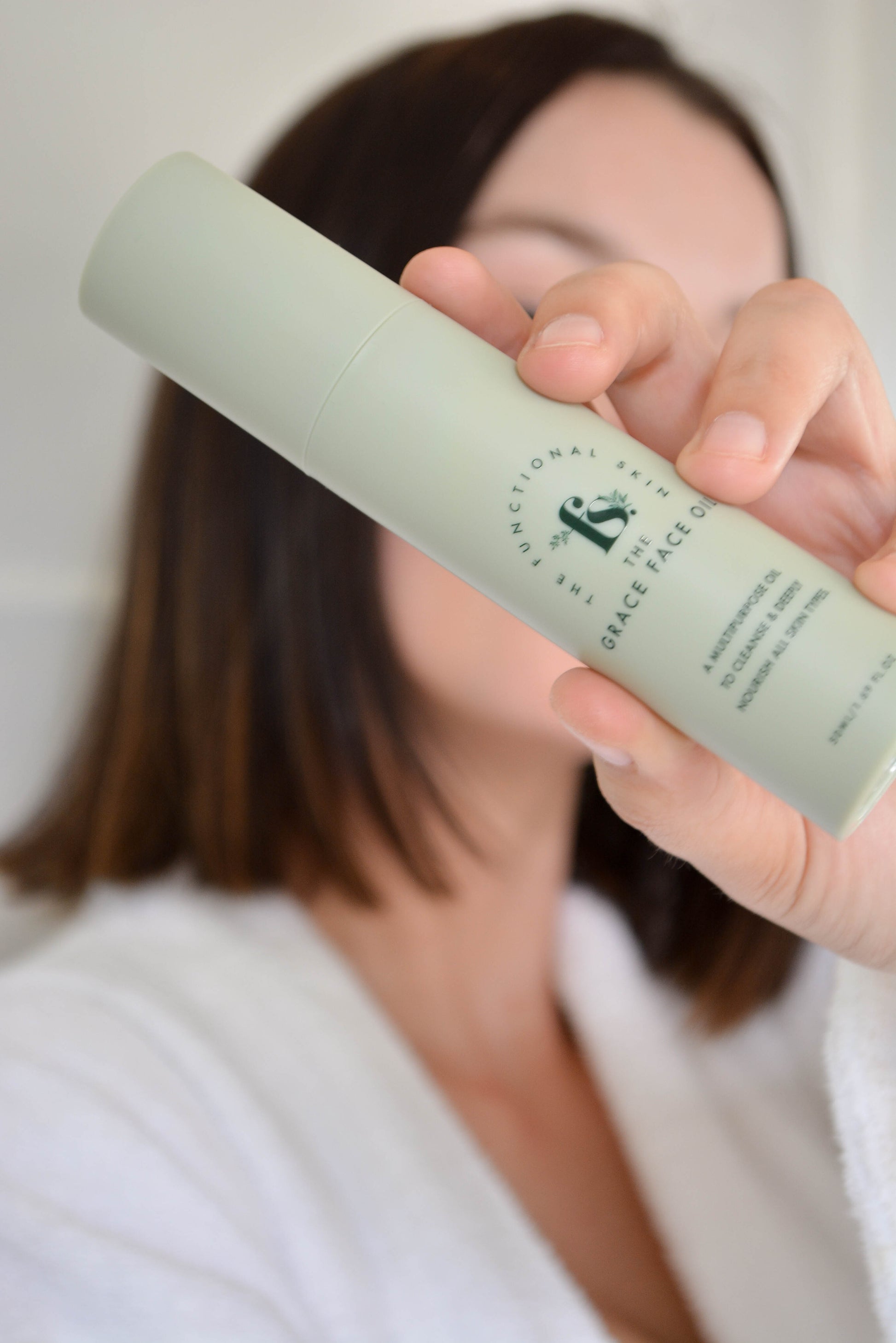 Women holding the grace face oil in front of her face 