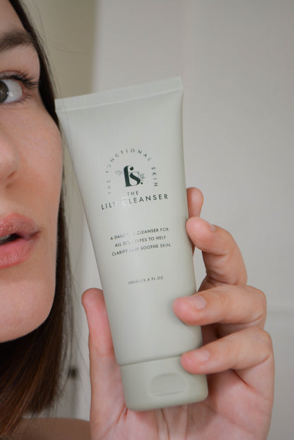 Bottle of the Lily Cleanser in front of a women's face in hand 