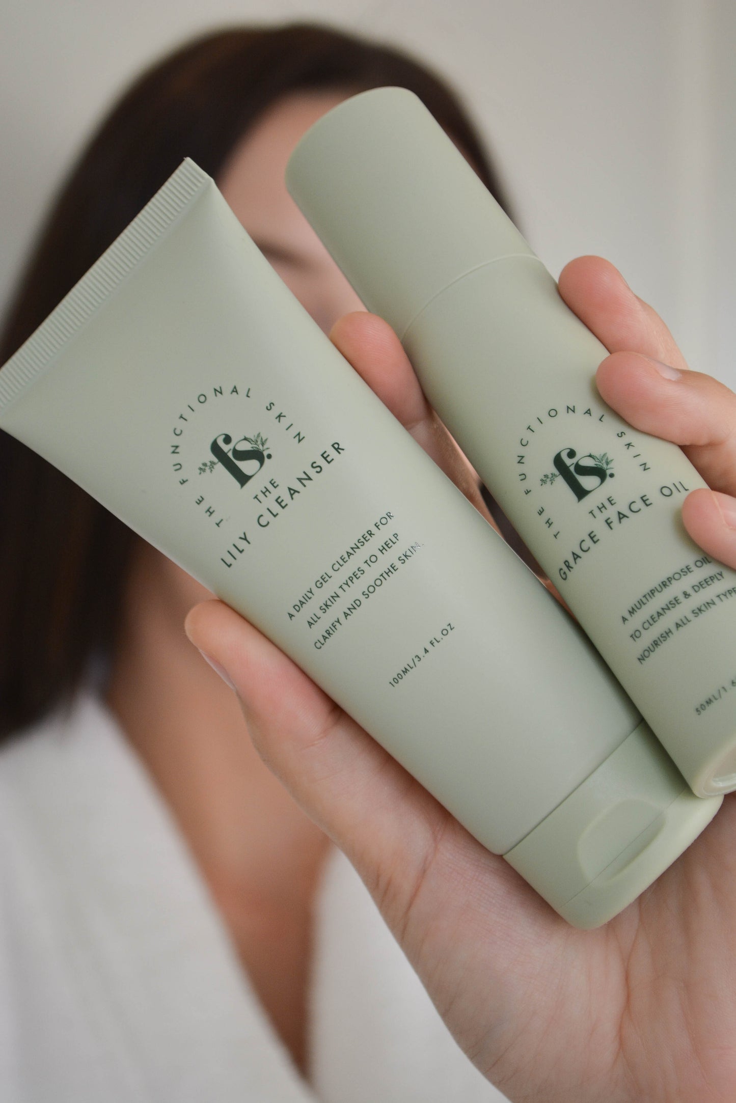 Women holding The lily cleanser and grace face oil  in front of face 